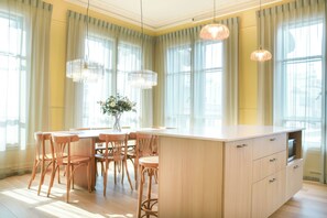 A modern kitchen with a central island, wooden chairs, and pendant lighting. - Les Lofts du Pont - Par Les Lofts (Québec)