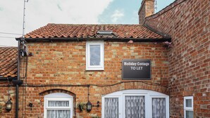 A brick cottage with a sign reading "Holiday Cottage to Let". - The Old Stables (Skegness)