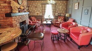 A cozy living room with a brick fireplace, red leather sofas, and a chandelier. - The Old Stables (Skegness)