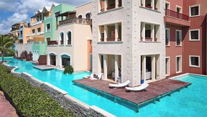 Ein Hotel mit Schwimmbad, farbenfrohen Gebäuden und einem turmartigen Bau.