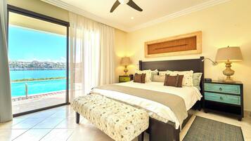 Un dormitorio con una cama grande, una mesita de noche, un banco y vistas a un cuerpo de agua.