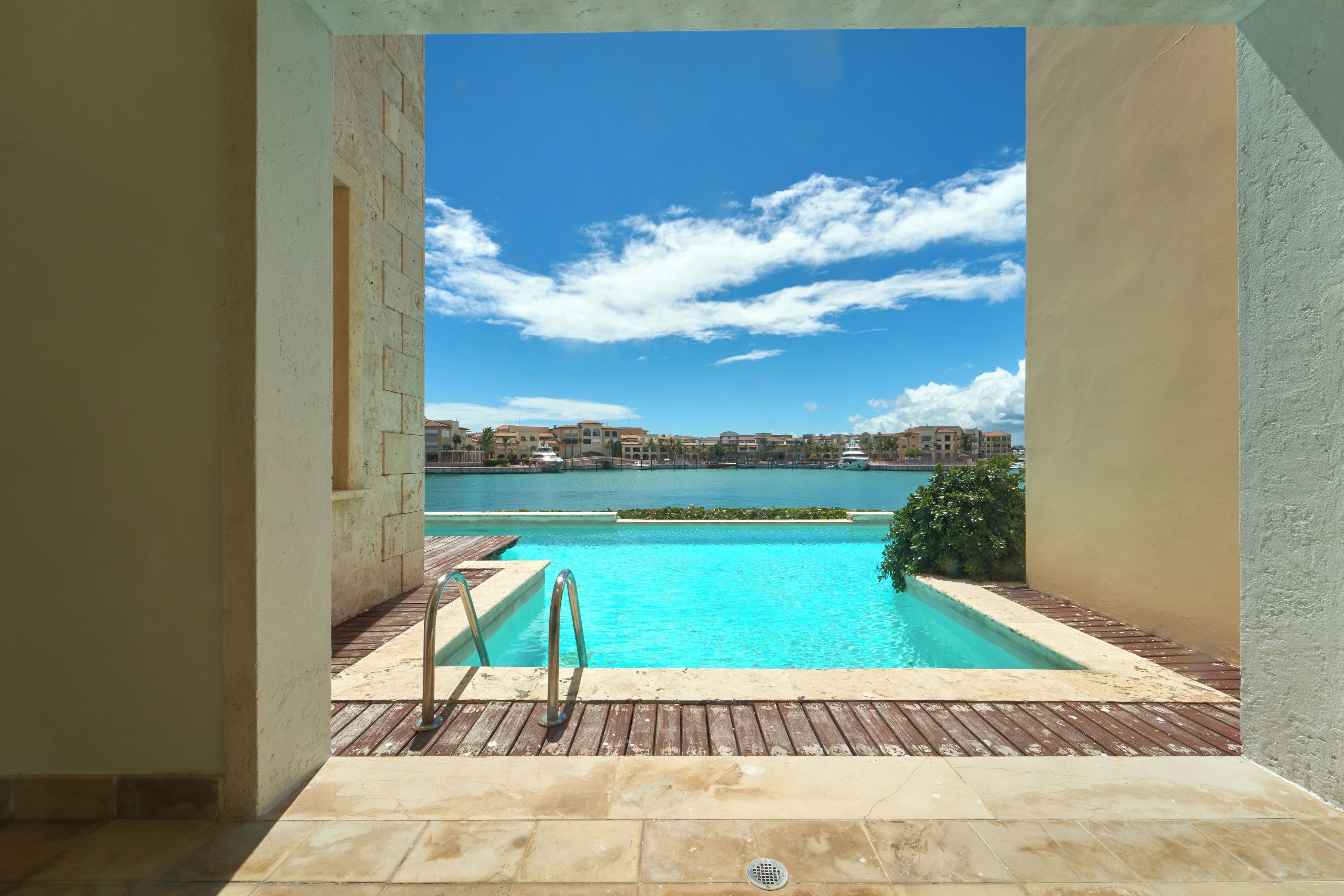 A swimming pool with a view of a body of water and distant buildings.