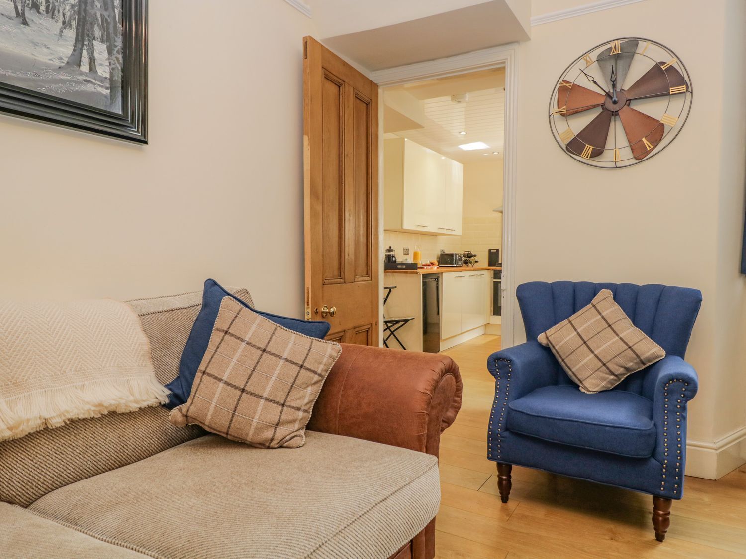 A living room with a sofa, a blue armchair, and a wall clock.