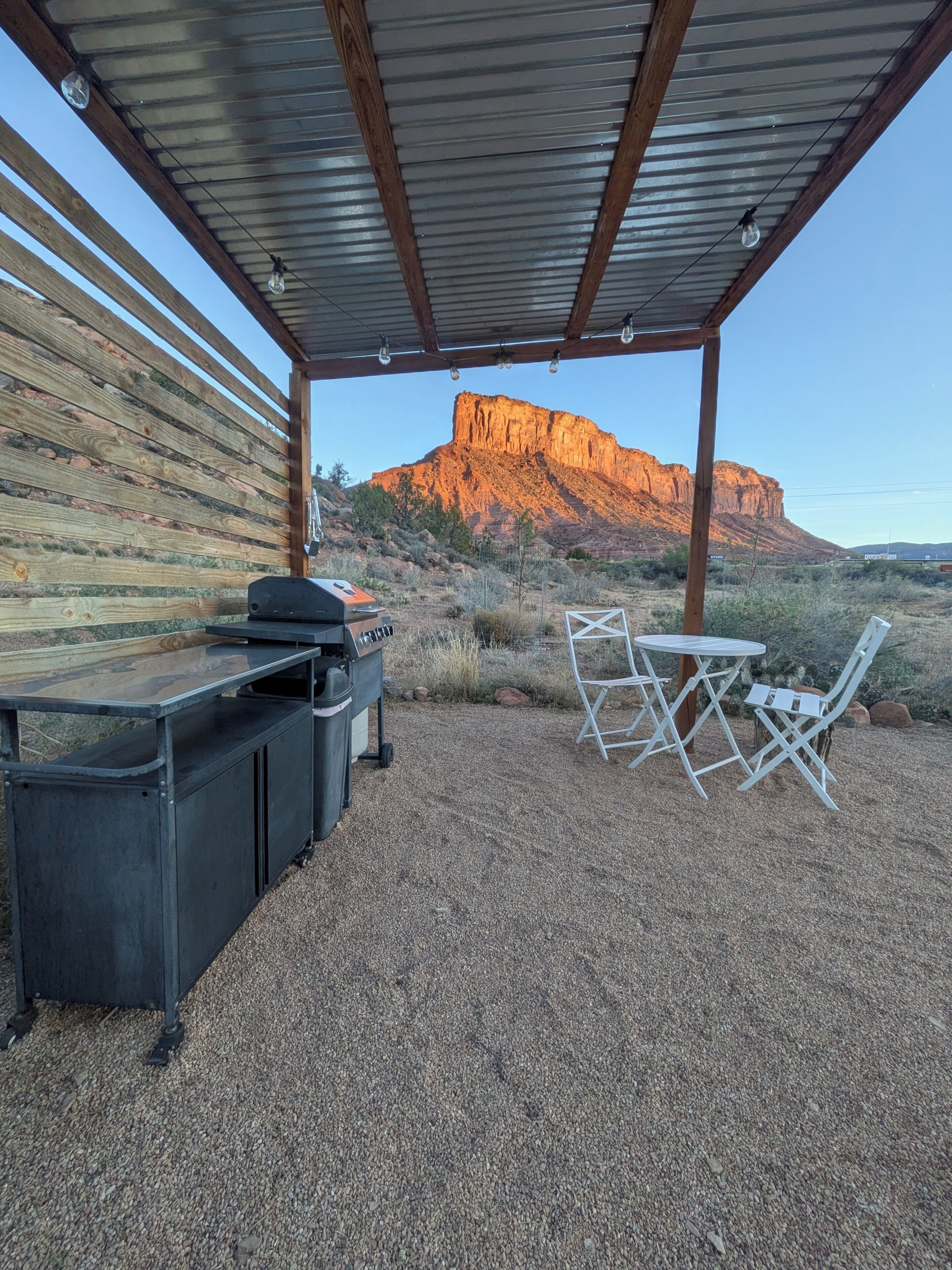 A covered outdoor area with a grill, seating, and a view of a mountain.