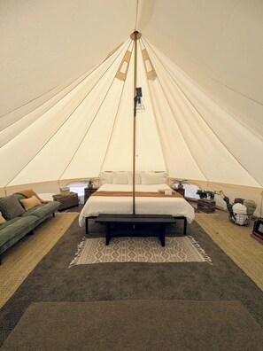 A tent with a bed, a bench, and a small table with a lamp. - Canyon Tent at Gateway Glamping, Western Colorado (Gateway)
