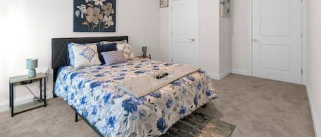 A bedroom with a bed, bedside tables, a lamp, and two doors.