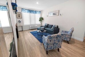 A modern living room with a blue sofa, patterned armchairs, a coffee table, and a blue rug. - Blue Bliss 2BR 2BTH with FREE Parking, Near NYC & EWR Airport (East Orange)