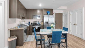 A modern kitchen with a dining area, stainless steel appliances, and a blue chair arrangement.