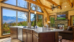 Une cuisine spacieuse avec de grandes fenêtres, une cheminée en pierre et un coin salon confortable.