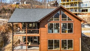 Una casa a due piani in legno con un balcone al piano superiore, ampie finestre e un tetto spiovente.