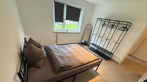 A small, single-bed room with a window, a radiator, a mirror, and a shoe rack. - Forest View - near Rußweiher (Eschenbach in der Oberpfalz)
