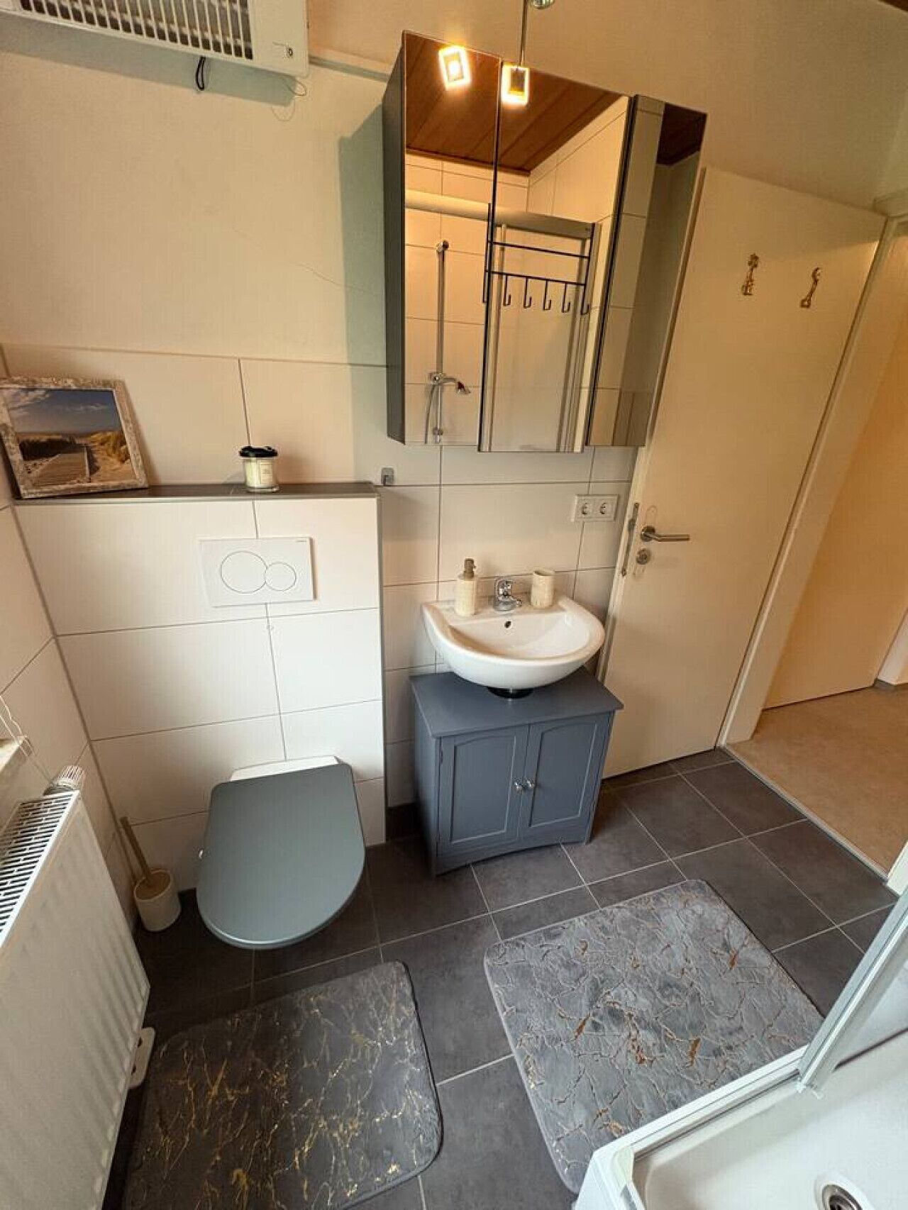 Een badkamer met toilet, wastafel en spiegel.
