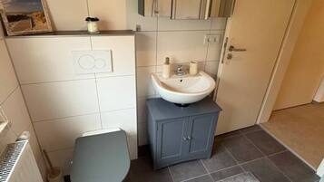 Een badkamer met toilet, wastafel en spiegel.