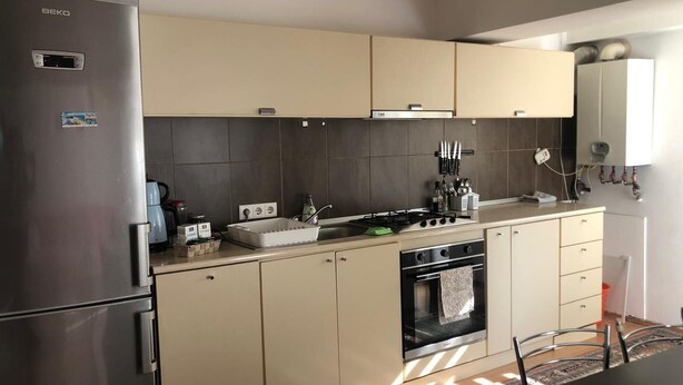 Eine moderne Küche mit einem Edelstahl-Kühlschrank, beigen Schränken, einem Einbauofen und einer Spüle.