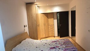 Ein Schlafzimmer mit einem Bett, einem Holzschrank und einer Tür zu einem anderen Raum.