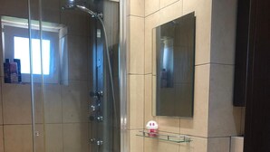 Ein modernes Badezimmer mit einer Duschkabine, einem weißen Waschbecken mit Spiegel darüber und einer Toilette.