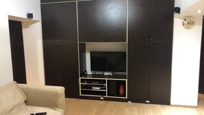 Ein Wohnzimmer mit großem Flachbildfernseher, einer Couch und Holzboden.