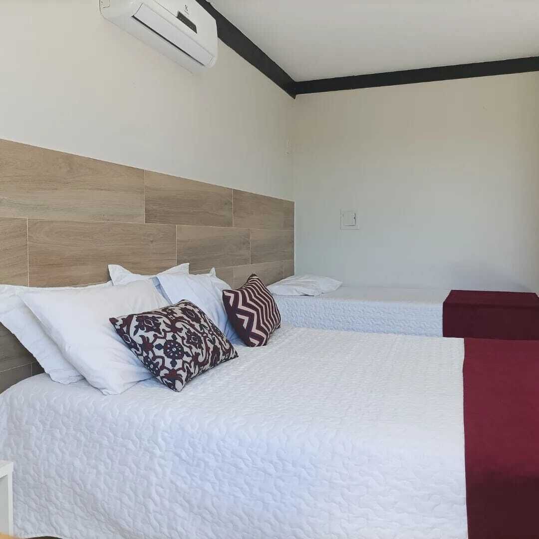 A hotel room with two beds, a wooden headboard, and a red accent wall.