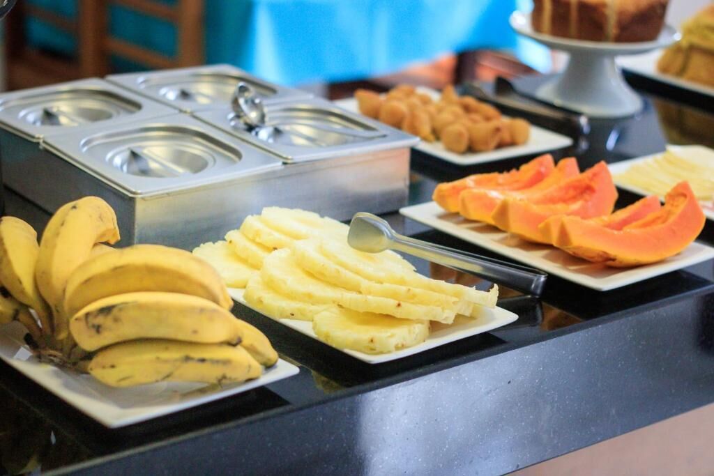 Un bufé con diversos alimentos, entre ellos plátanos, puré de papas y fruta en rodajas.