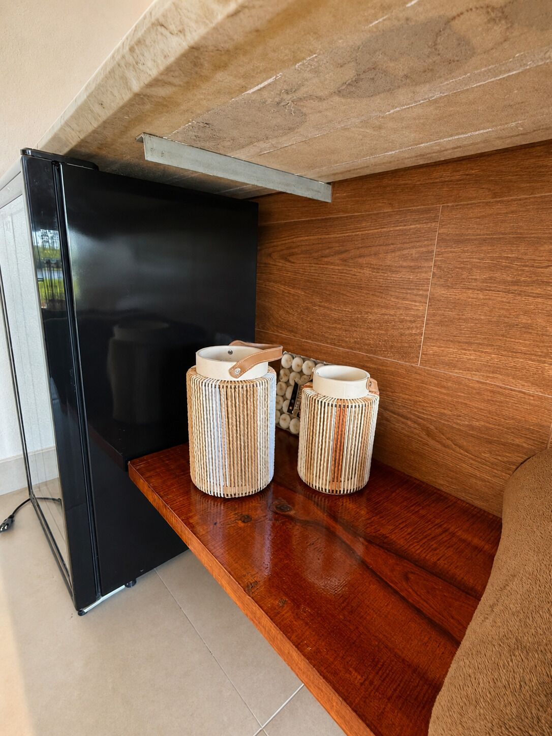 A modern kitchen with a black refrigerator, wooden cabinets, and two cylindrical containers on a wooden countertop.
