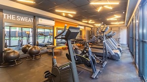 Une salle de sport équipée de tapis de course, de ballons d’exercice et de poids.