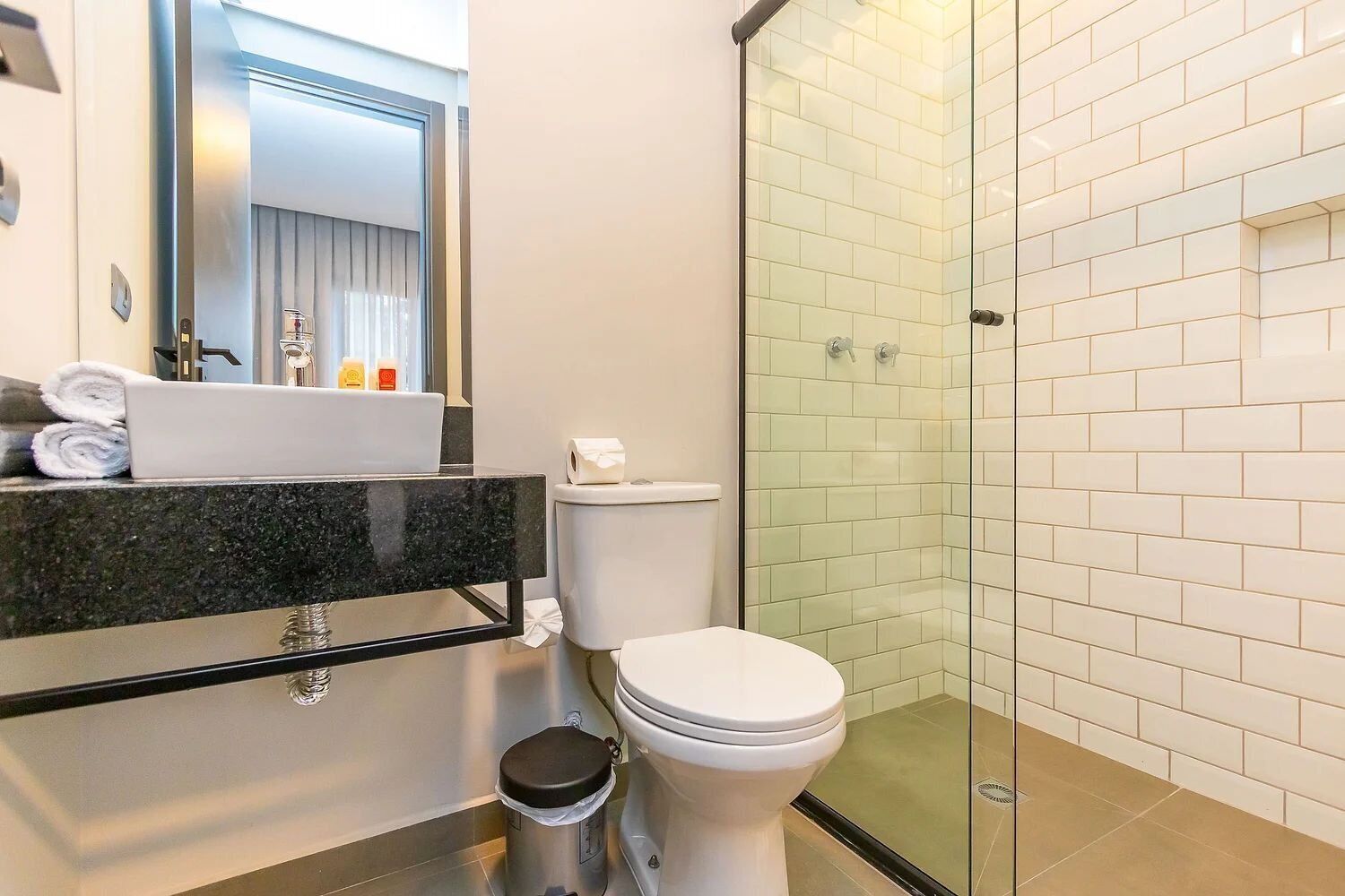 A modern bathroom with a glass-enclosed shower, a white toilet, and a granite countertop with a sink.
