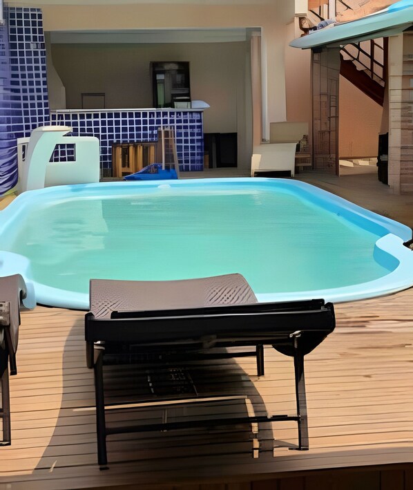 Ein Pool mit Liegestuhl und kleinem Tisch, umgeben von einer Holzterrasse.