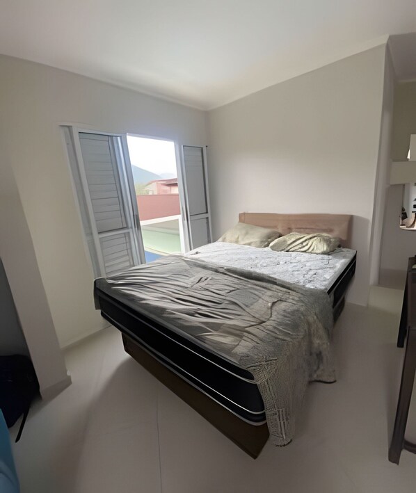 A bedroom with a bed, a window, and a door. - House with pool in Maresias - SP (1) (Sao Sebastiao)