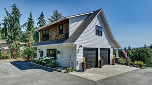 A two-story house with a garage, surrounded by trees and a clear sky. - Charming 1-bedroom house with WiFi, AC , laundry in lovely Snohomish (Snohomish)