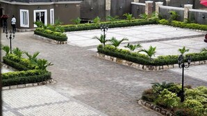 A courtyard with paved walkways, surrounded by neatly trimmed hedges and palm trees. - Brava Hotel (Ibadan)