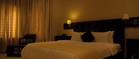 Une chambre d’hôtel avec un grand lit, une table de chevet, une chaise et une lampe.