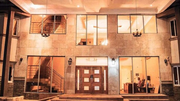 A hotel entrance with a stone facade, large glass doors, and a staircase leading to an upper level. - Brava Hotel (Ibadan)
