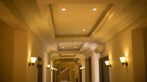 A hotel hallway with recessed lighting, wall sconces, and a staircase in the distance. - Brava Hotel (Ibadan)