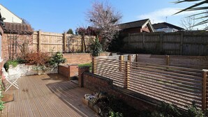 A wooden deck with a brick wall and a wooden fence. - Rose Cottage (Cottingham)