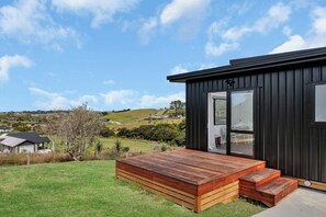 A modern house with a wooden deck and large windows. - Central Couples Retreat - Mangawhai Heads Unit (Mangawhai)