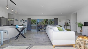 Eine moderne Küche mit Essbereich, einem weißen Sofa und einem großen Fenster.