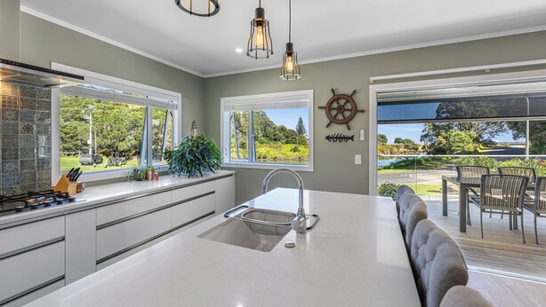 A modern kitchen with a large island, stainless steel appliances, and a view of the outdoors. - The Lighthouse - Te Mata Holiday Home (Thames)