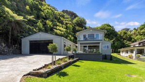 A modern two-story house with a garage, a balcony, and a well-maintained lawn. - The Lighthouse - Te Mata Holiday Home (Thames)