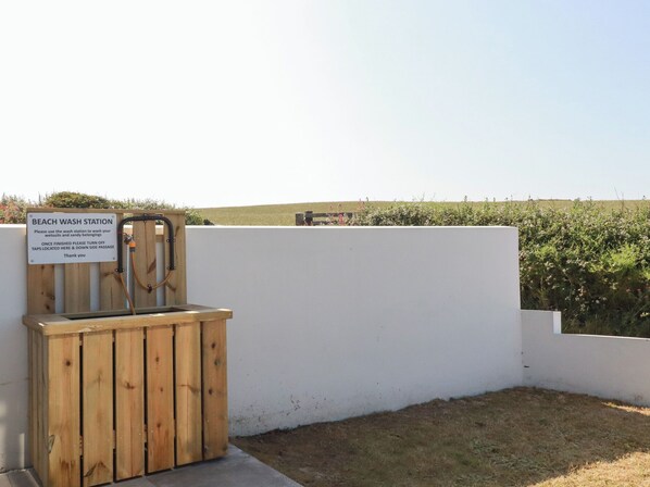A beach wash station with a wooden gate and a sign.