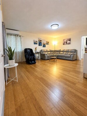 A living room with a grey sofa, a massage chair, a small table with a potted plant, and a lamp. - 2BR Apt: Close to Temple City, Arcadia & Pasadena (San Gabriel)