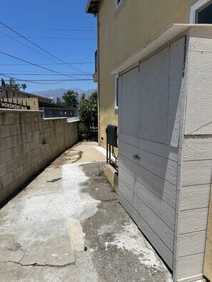 A narrow concrete pathway leading to a garage door, with a wall on one side and a fence on the other. - 2BR Apt: Close to Temple City, Arcadia & Pasadena (San Gabriel)