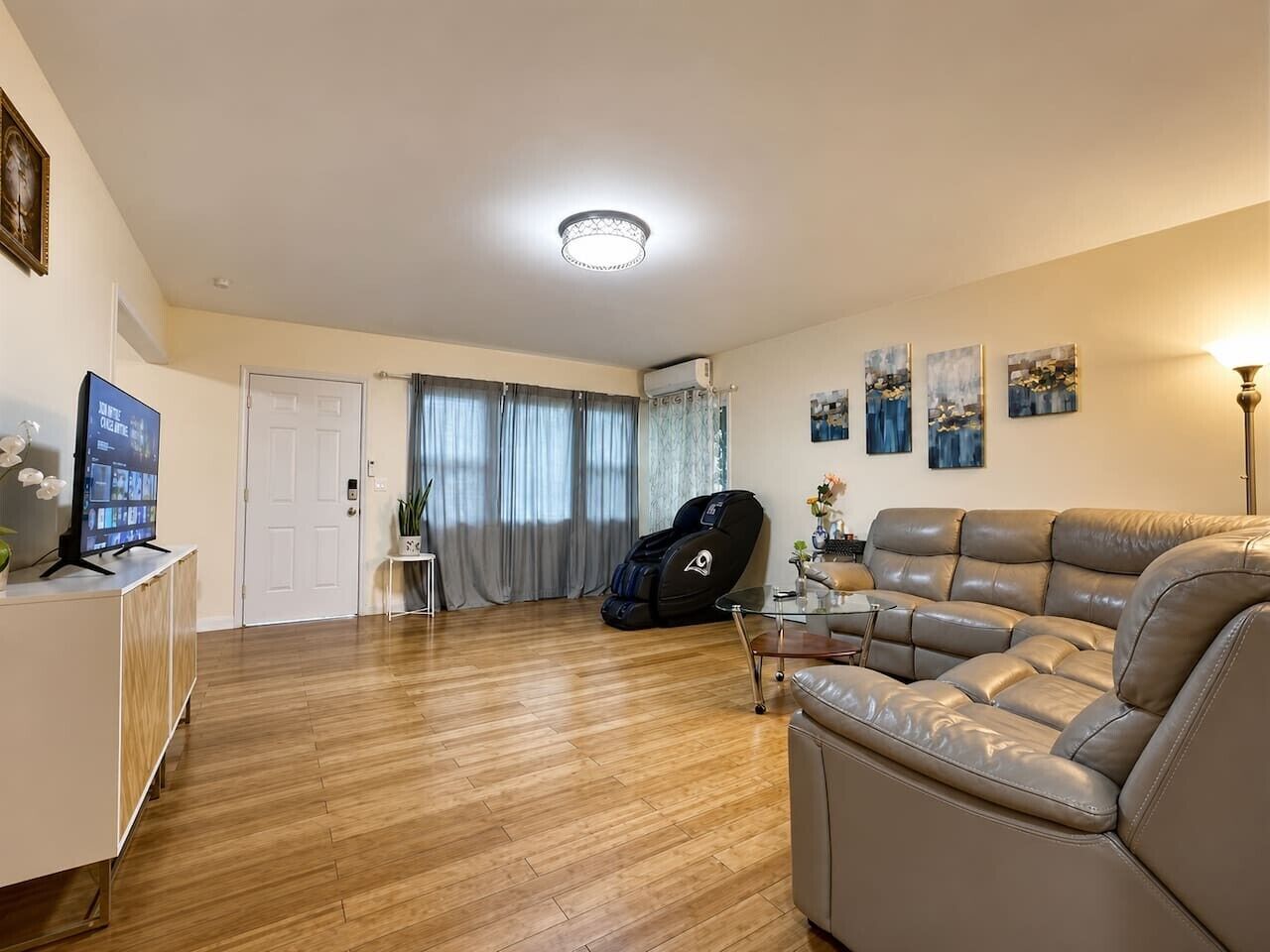 A living room with a leather sofa, a glass coffee table, and a television on a cabinet.