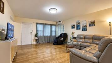 A living room with a leather sofa, a glass coffee table, and a television on a cabinet.