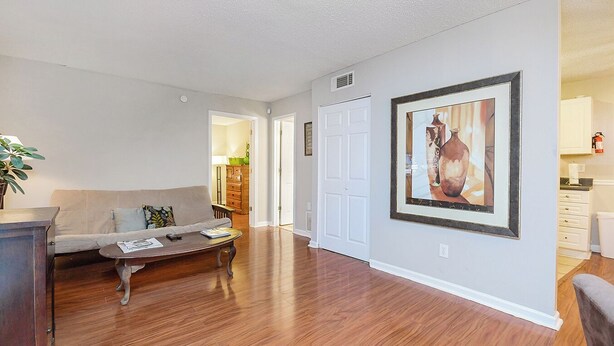 A living room with a sofa, coffee table, and a painting on the wall.