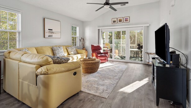 A spacious living room with a yellow sofa, a black entertainment unit, and a ceiling fan. - Ocean Keys 2 Blocks To The Ocean (North Myrtle Beach)
