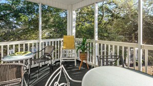 A covered outdoor seating area with wicker chairs, a yellow chair, and a table with a plant. - Ocean Keys 2 Blocks To The Ocean (North Myrtle Beach)