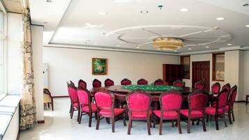 A conference room with a round table, red chairs, and a chandelier.