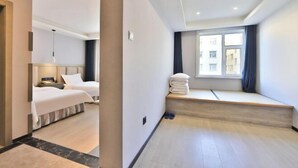 A hotel room with two beds, a window seat, and a view of buildings. - Yong Xu Hotel (Antu)