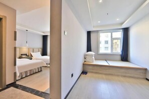 A hotel room with two beds, a window seat, and a view of buildings. - Yong Xu Hotel (Antu)