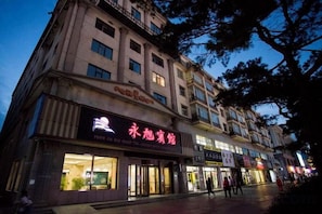 A multi-story building with illuminated signage, a storefront, and a pedestrian walkway. - Yong Xu Hotel (Antu)